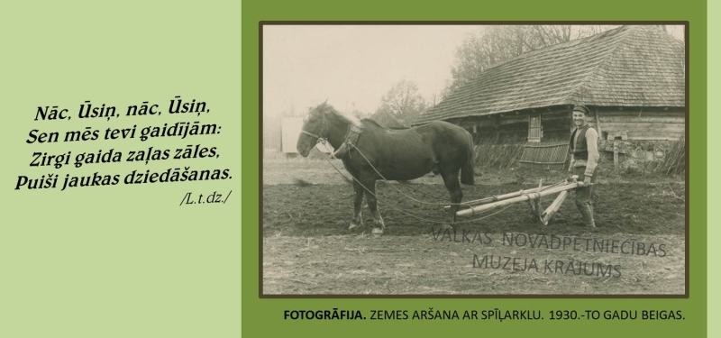 Melnbalta fotogrāfija. Redzama zemes aršana ar spīļarklu. Fonā koka ēka, priekšplānā sirgs un vīrietis.