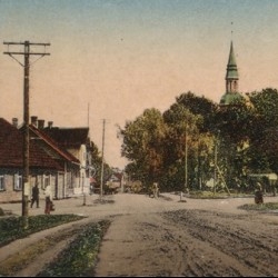 Valkas pilsētas skats ar baznīcas torni tālumā, kas atspoguļo pilsētas arhitektūru un gaisotni 20. gadsimta sākumā.