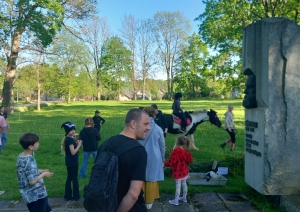 Zirgu izjādes aploks muzeja pļavā. Bērni un vecāki gaida izjādes rindā. Zemnieku saimniecības "Kurģi"  zirgi aplokā. Uz Tinker šķirnes zirga, meitenīte izjādē.  Pavadone pieved poniju uz izjādes sākumu vietu.